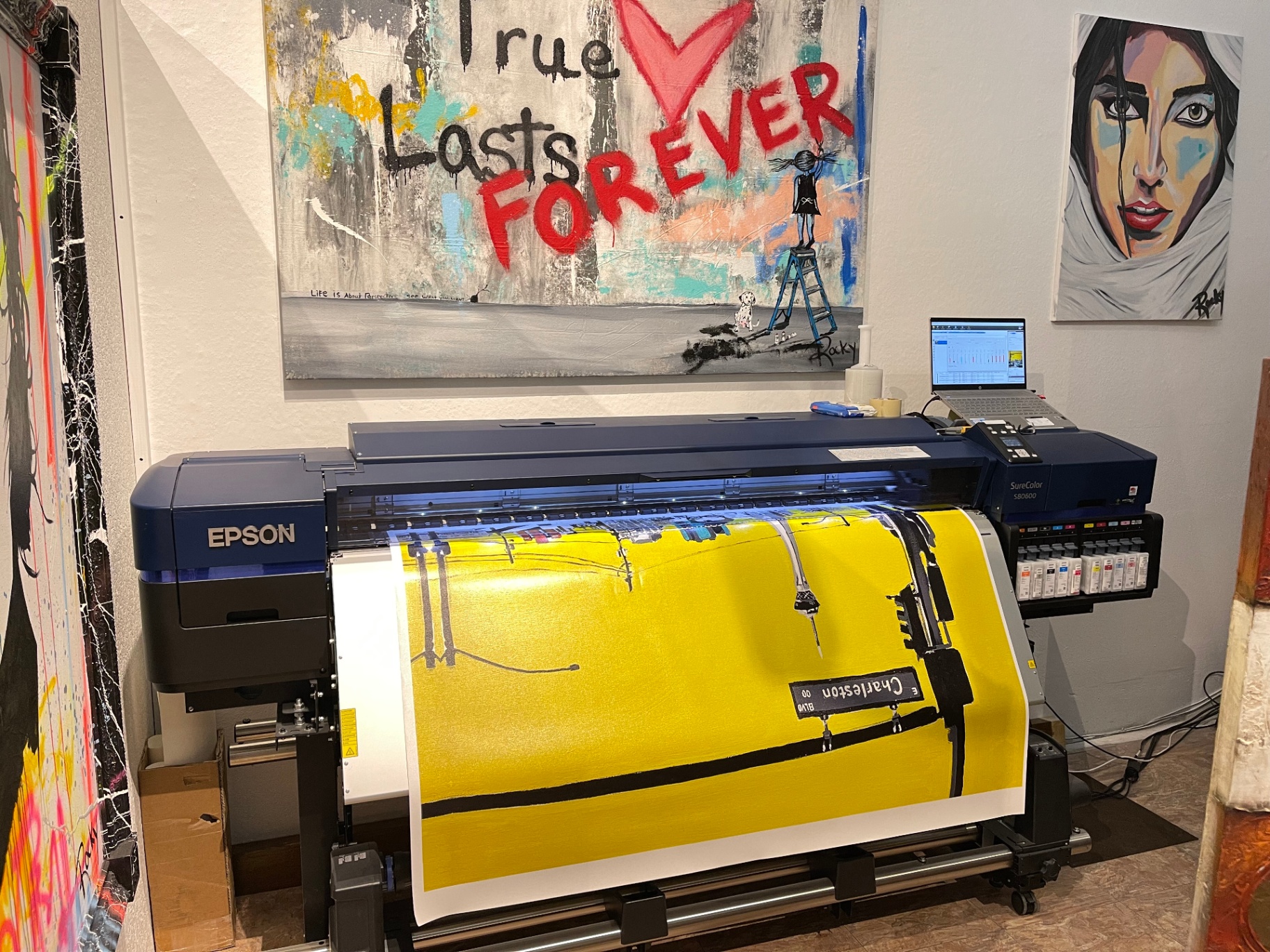 Wide-format Epson printer in the ART 2 art studio with vibrant artworks on the wall.